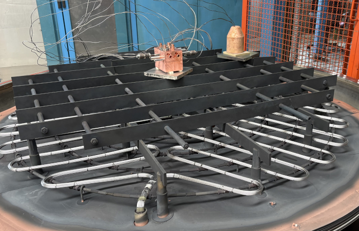 interno di forno per brasature in vuoto, si vede una griglia di supporti metallici, la resistenze per il riscaldamento e due coampioni di rame a cui sono collegate delle termocoppie