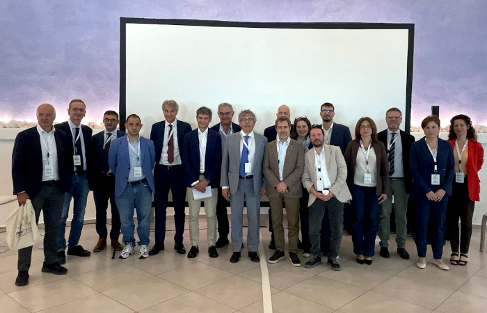 foto di gruppo con numerose persone in piedi davantia un pannello bianco