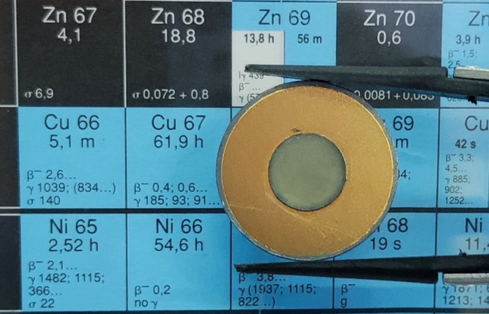 circular target made of ZnO hold with tweezers on a radionuclides table
